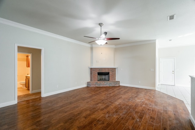 unfurnished living room featuring ceiling fan, wood-type flooring, ornamental molding, and a brick fireplace