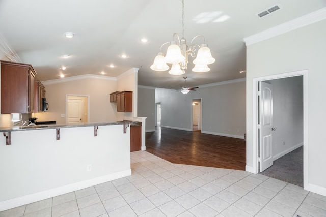 kitchen with a kitchen breakfast bar, ornamental molding, decorative light fixtures, and light wood-type flooring