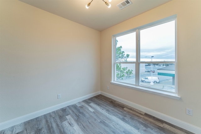 unfurnished room with wood-type flooring and a chandelier