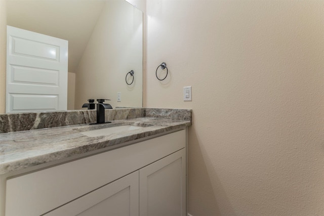 bathroom with lofted ceiling and vanity