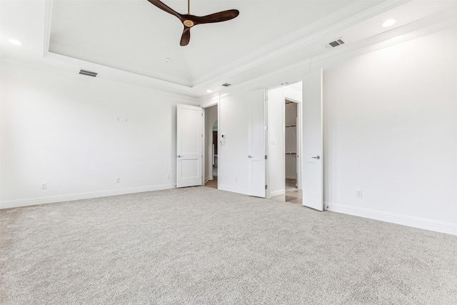 carpeted empty room with crown molding, a tray ceiling, and ceiling fan