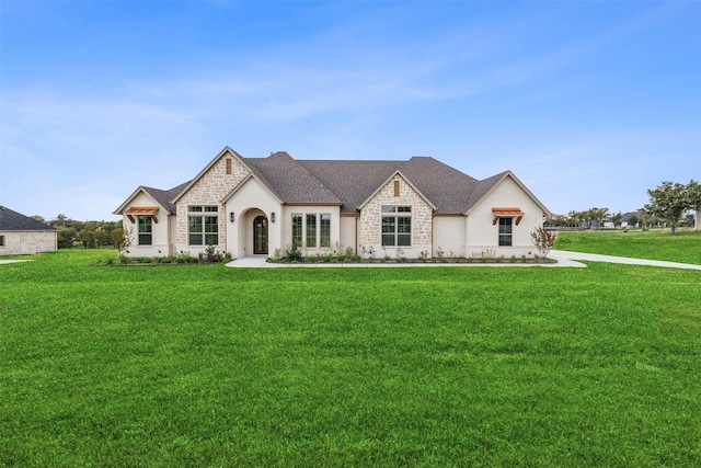 french provincial home featuring stone siding, a front lawn, and a shingled roof