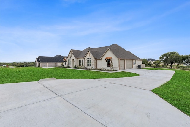 view of front of home featuring an attached garage, driveway, stone siding, and a front yard