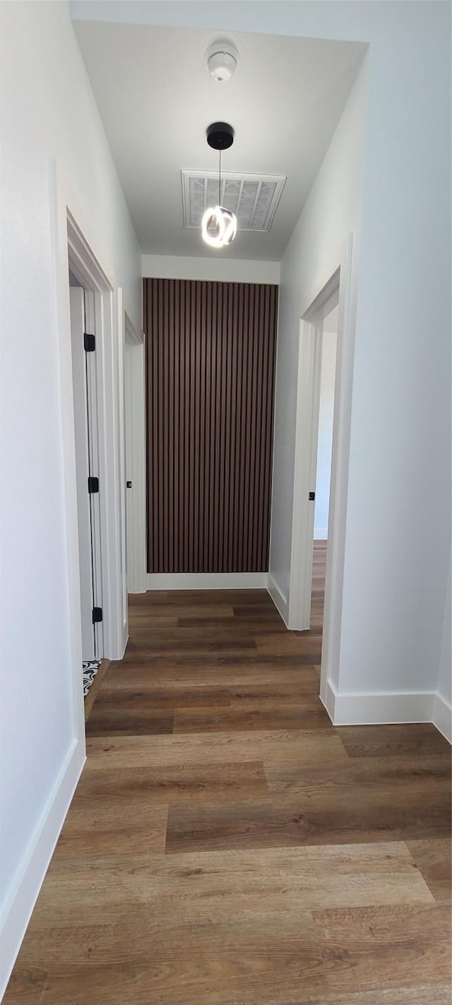 hallway with visible vents, baseboards, and wood finished floors