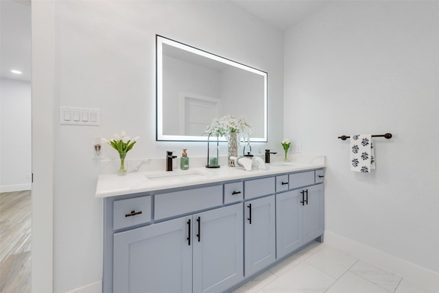 bathroom featuring double vanity, baseboards, and a sink