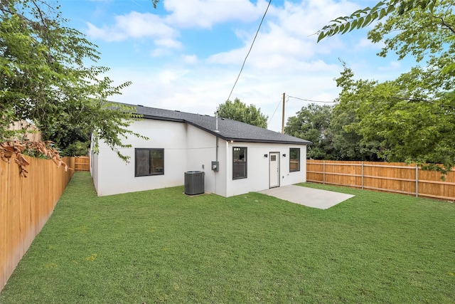 rear view of property featuring central air condition unit, a lawn, a fenced backyard, and stucco siding