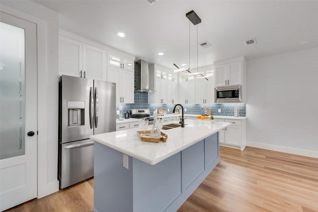 kitchen featuring a sink, decorative backsplash, appliances with stainless steel finishes, and wall chimney range hood