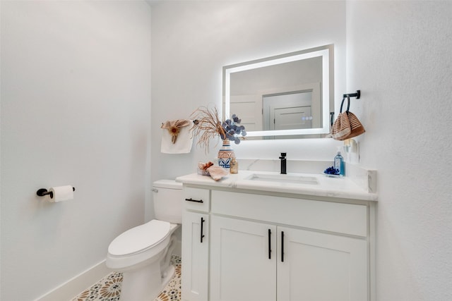 half bath featuring baseboards, toilet, vanity, and tile patterned flooring