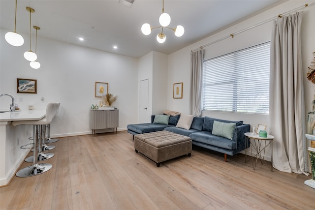 living room with an inviting chandelier, sink, and light wood-type flooring