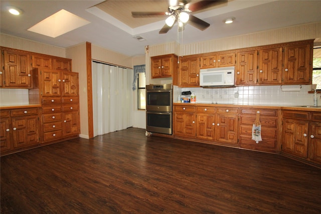 kitchen with dark hardwood / wood-style floors, tasteful backsplash, sink, ceiling fan, and double oven