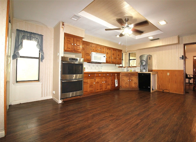 kitchen with stainless steel double oven, a healthy amount of sunlight, a raised ceiling, and ceiling fan