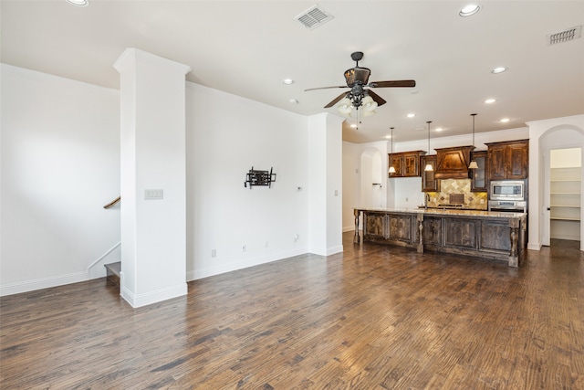 unfurnished living room featuring ceiling fan and dark hardwood / wood-style flooring