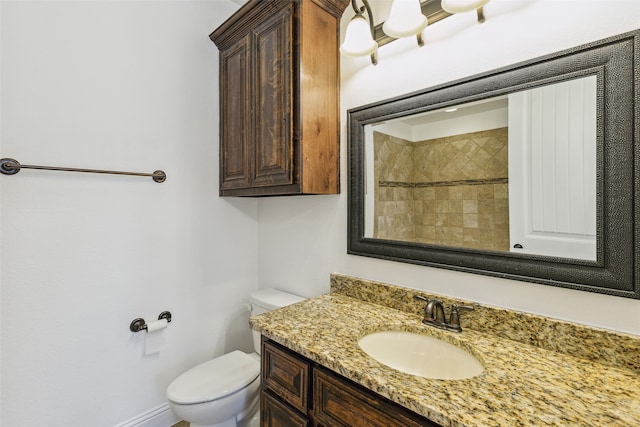 bathroom featuring tiled shower, toilet, and vanity