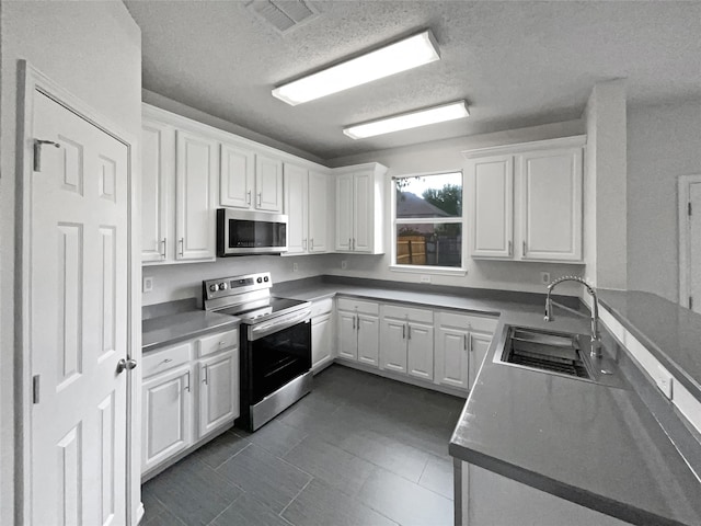 kitchen with appliances with stainless steel finishes, white cabinetry, sink, and a textured ceiling