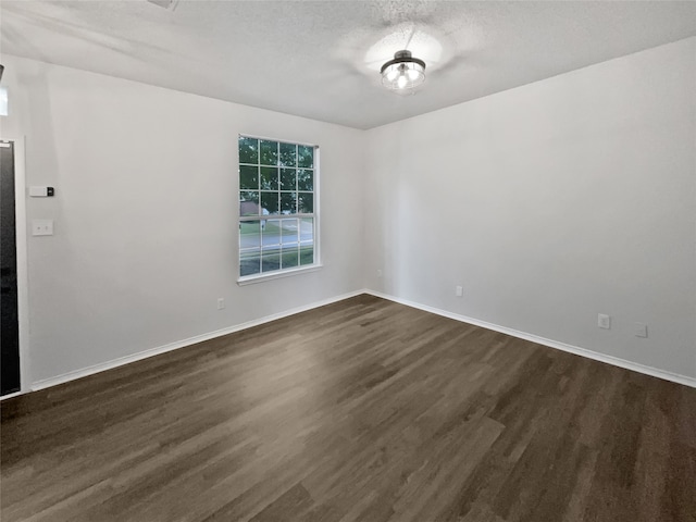 spare room with a textured ceiling and dark hardwood / wood-style floors