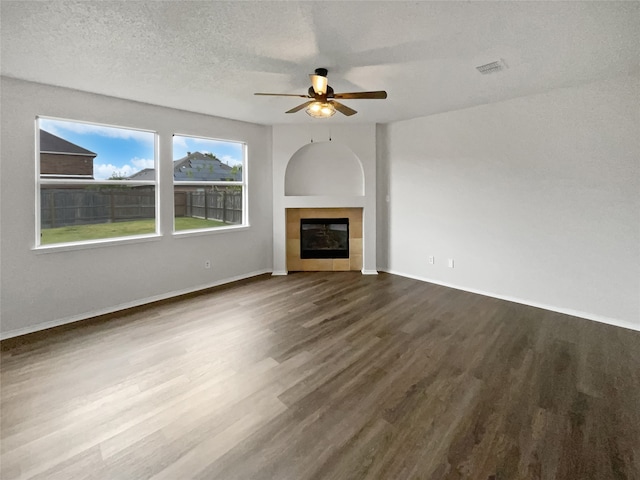 unfurnished living room featuring a wealth of natural light, wood-type flooring, ceiling fan, and a tile fireplace