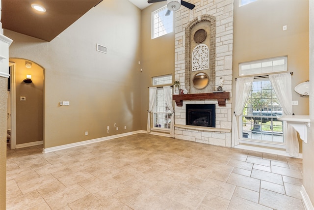 unfurnished living room with a high ceiling, a fireplace, and ceiling fan