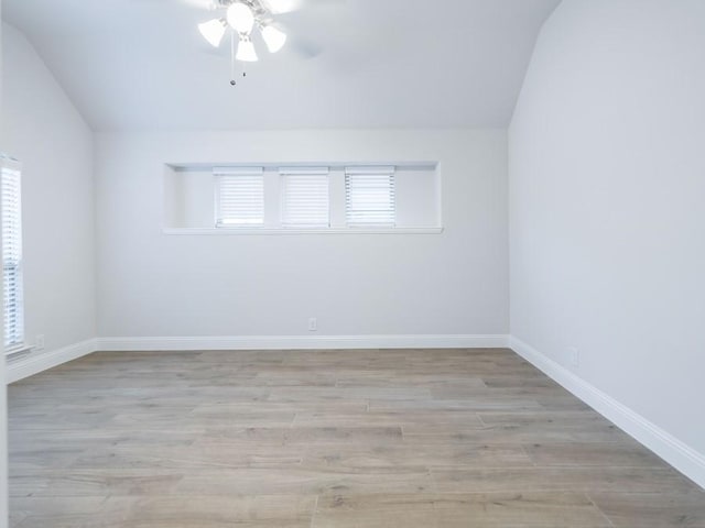 spare room with light hardwood / wood-style floors, a wealth of natural light, and lofted ceiling