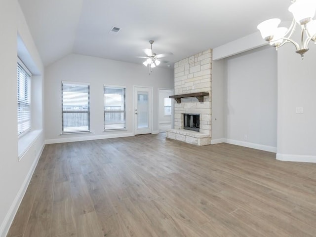 unfurnished living room with lofted ceiling, a fireplace, ceiling fan with notable chandelier, and light wood-type flooring