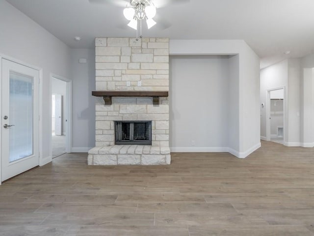 unfurnished living room featuring a fireplace, light hardwood / wood-style floors, and ceiling fan