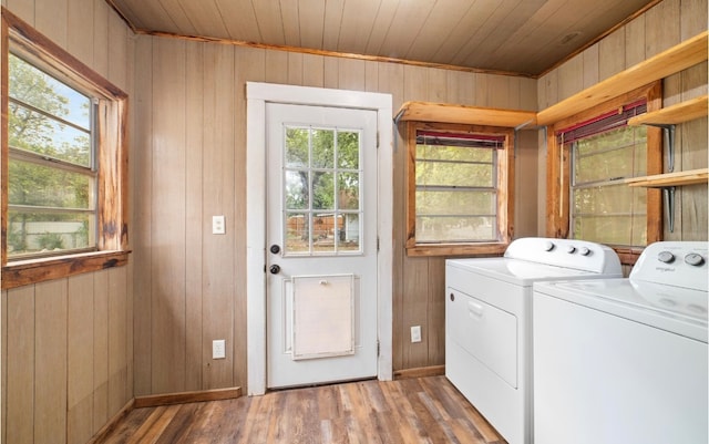 clothes washing area featuring washing machine and dryer, wood ceiling, wooden walls, and light hardwood / wood-style floors