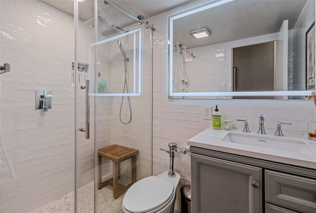 bathroom featuring toilet, a shower with door, vanity, decorative backsplash, and tile walls