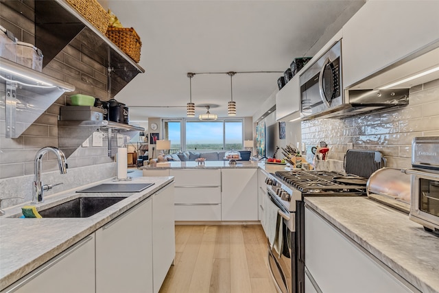 kitchen with white cabinets, stainless steel appliances, light hardwood / wood-style floors, sink, and tasteful backsplash