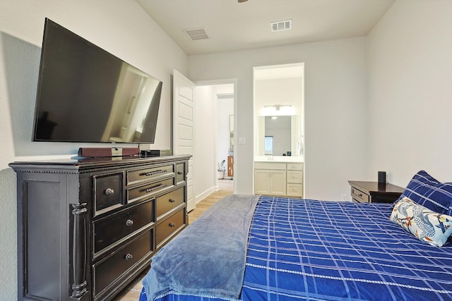 bedroom featuring light hardwood / wood-style flooring and ensuite bath