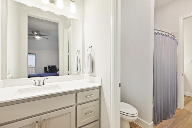 bathroom featuring wood-type flooring, vanity, toilet, and ceiling fan