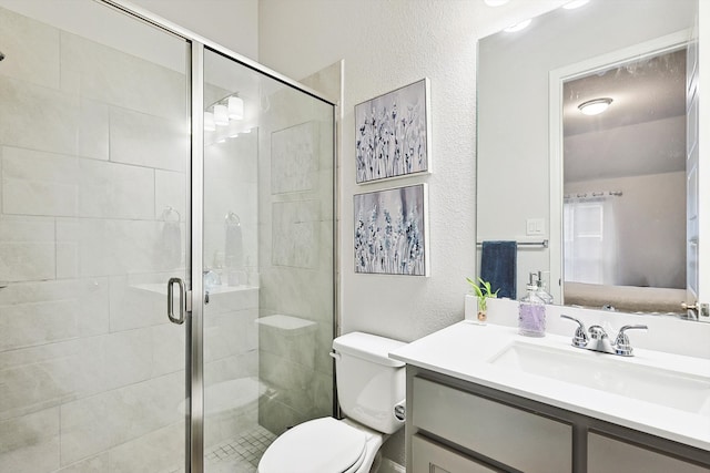 bathroom with a shower with shower door, vanity, and toilet