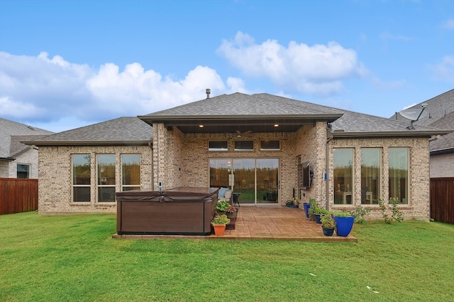 back of house with a lawn, a hot tub, and a patio area