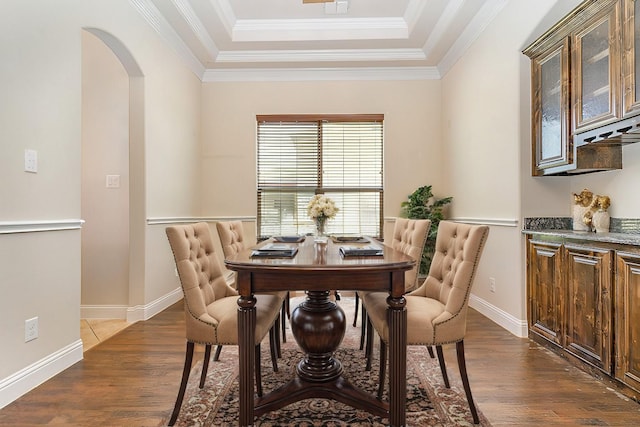 dining room featuring a tray ceiling, crown molding, and dark hardwood / wood-style flooring