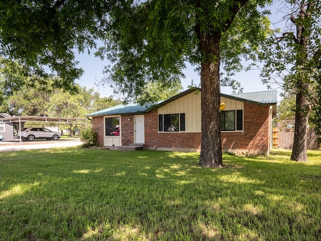 ranch-style house featuring brick siding, a carport, and a front yard