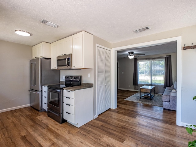 kitchen with appliances with stainless steel finishes, dark countertops, white cabinets, and visible vents