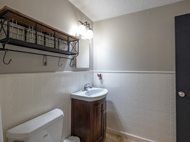 bathroom featuring a textured ceiling, vanity, tasteful backsplash, tile walls, and toilet