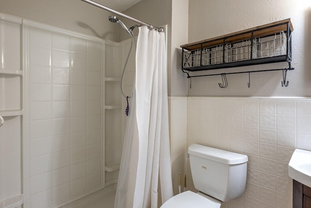 bathroom featuring toilet, a stall shower, tile walls, and wainscoting