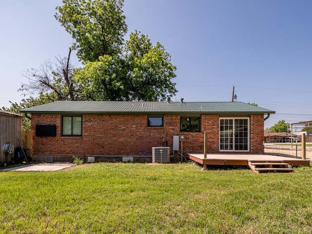 rear view of property featuring a yard, a wooden deck, and central air condition unit