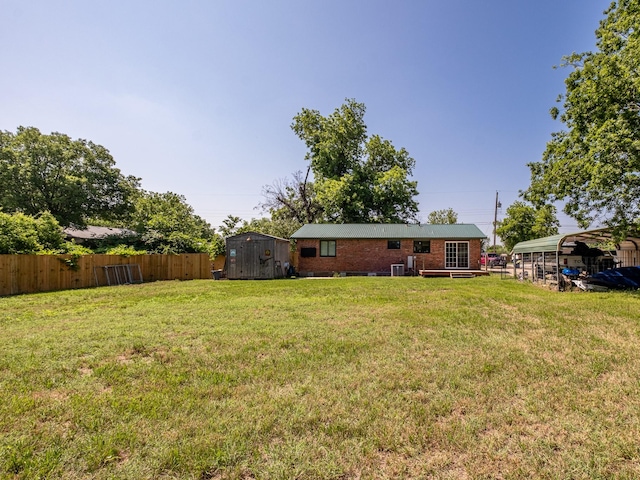 view of yard featuring a storage unit, an outdoor structure, fence, and a detached carport