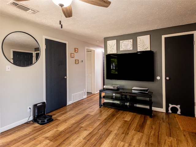 living room with a textured ceiling, hardwood / wood-style floors, and ceiling fan