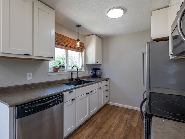 kitchen featuring dark hardwood / wood-style floors, decorative light fixtures, stainless steel appliances, sink, and white cabinetry