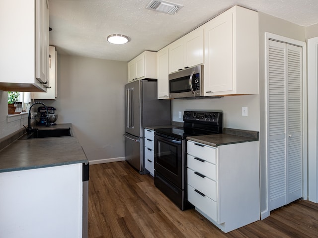 kitchen with a textured ceiling, sink, dark wood-type flooring, appliances with stainless steel finishes, and white cabinets