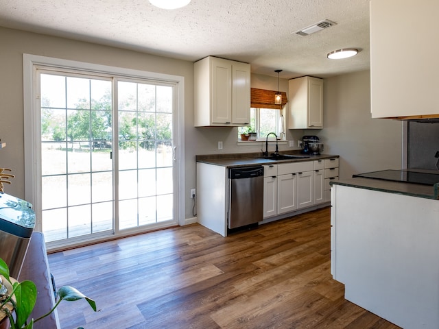 kitchen featuring a textured ceiling, decorative light fixtures, dishwasher, wood-type flooring, and sink