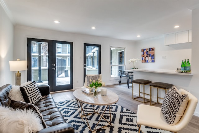 living room with light wood-type flooring, crown molding, and french doors