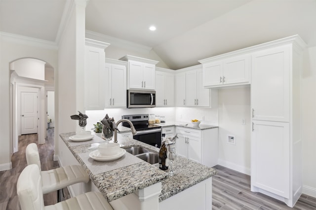 kitchen with white cabinets, sink, stainless steel appliances, and a breakfast bar area