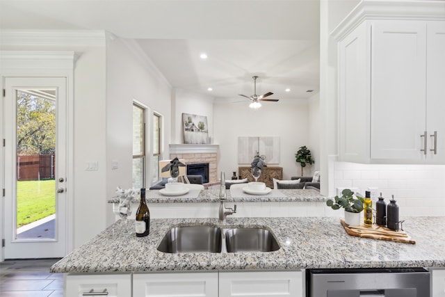 kitchen featuring light stone countertops, white cabinetry, and sink