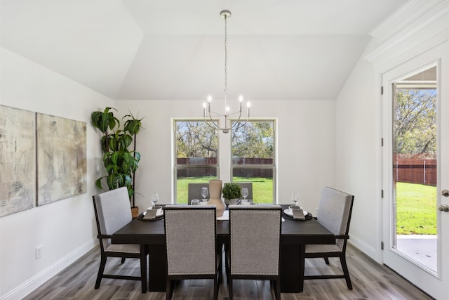 dining area with hardwood / wood-style floors, plenty of natural light, lofted ceiling, and an inviting chandelier