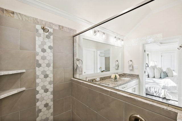 bathroom featuring a tile shower, vaulted ceiling, and crown molding