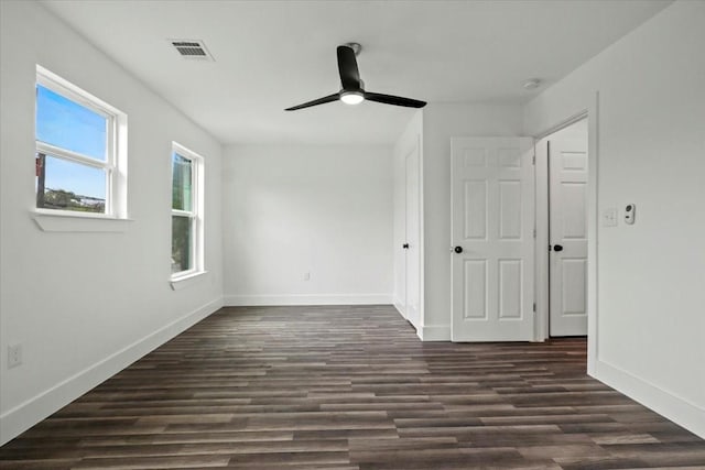 unfurnished room featuring dark wood finished floors, visible vents, and baseboards