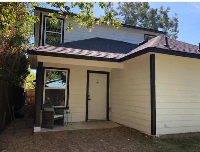 back of house with a patio, roof with shingles, and fence