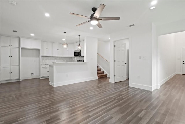 unfurnished living room featuring dark wood-style flooring, visible vents, stairway, ceiling fan, and baseboards